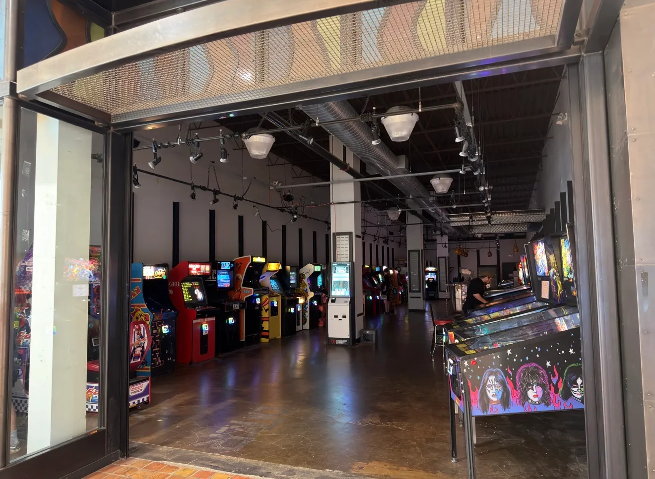 The Mayhem Amusements Arcade floor — rows of classic arcade cabinets and a pinball machine.